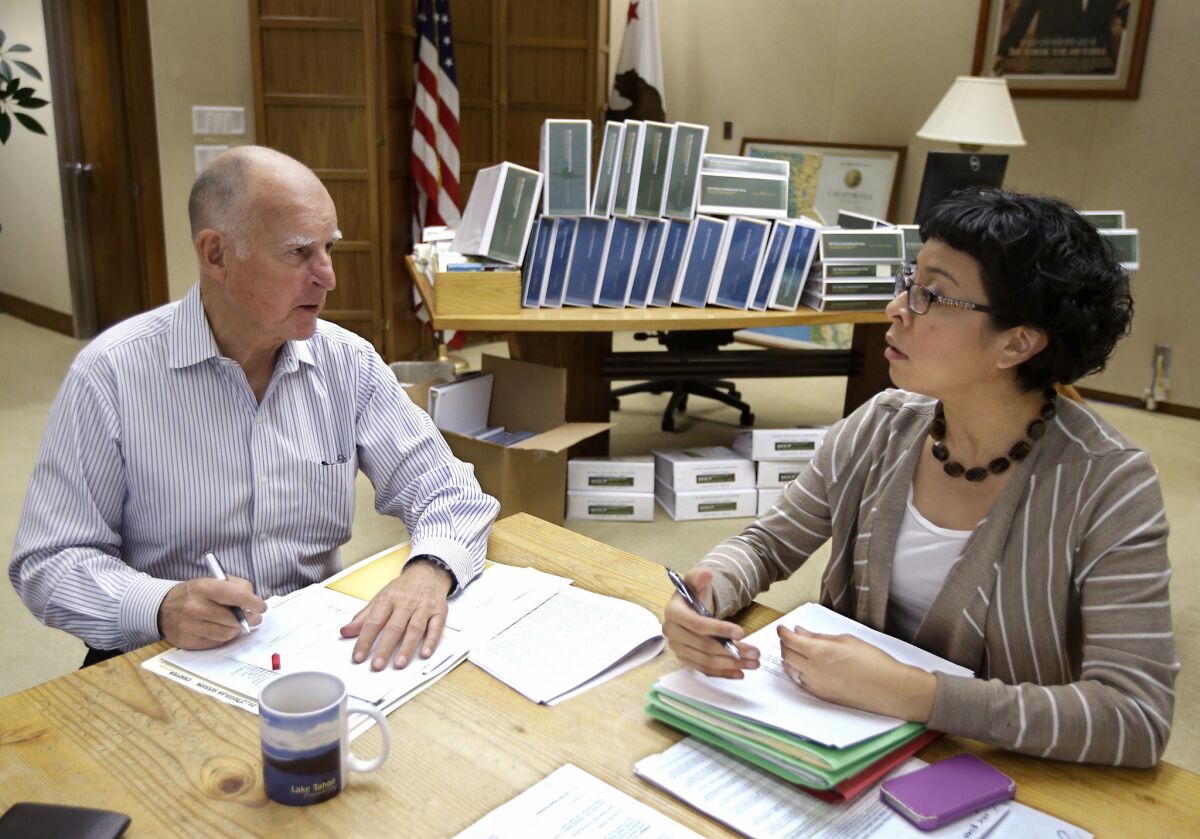 California Gov. Jerry Brown discusses a bill he is about to sign with Graciela Castillo-Kring his deputy legislative secretary, at his Capitol office in Sacramento, Calif.