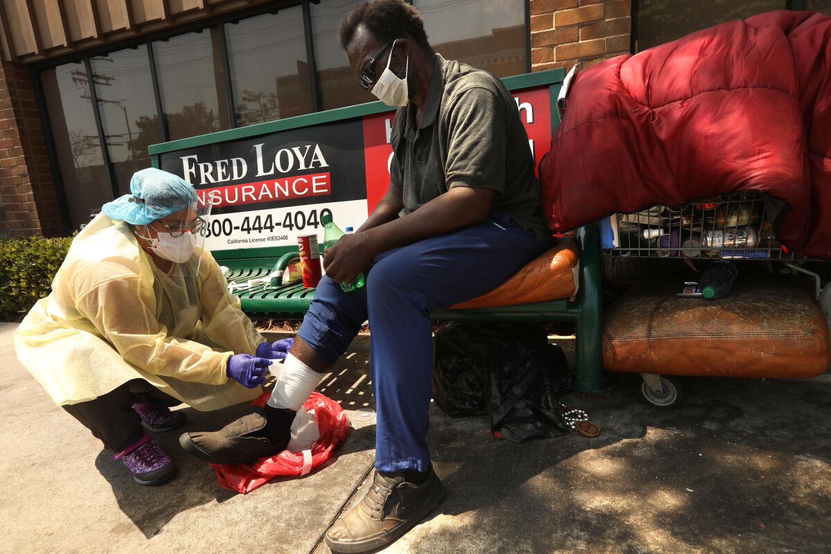 Nurse Richelle Legaspi helps bandage a wound on Pookie Moore’s leg in East Hollywood. 