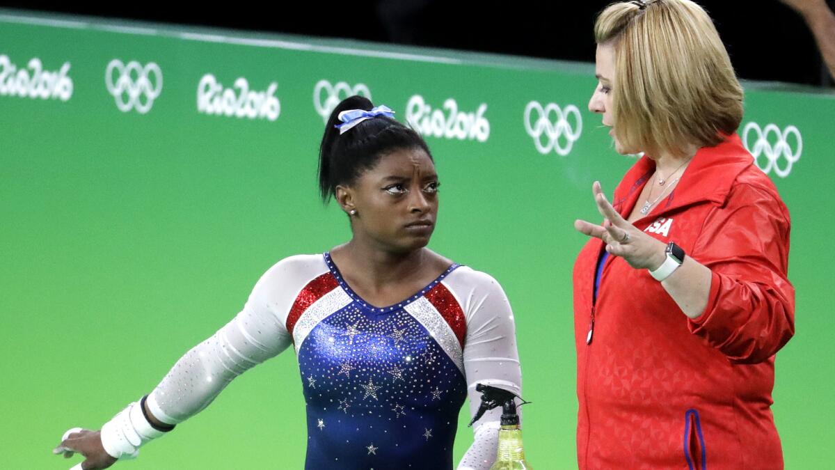 Coach Aimee Boorman talks to gymnast Simone Biles between routines during her gold medal-winning all-around performance on Aug. 11.