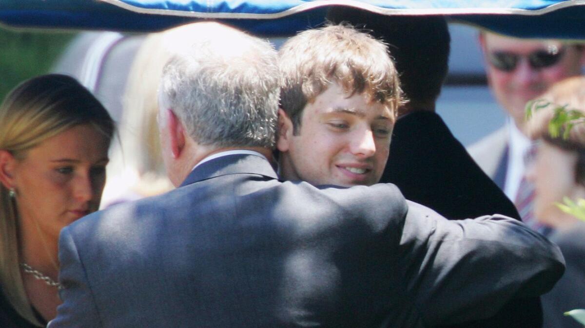 John Ramsey hugs his son Burke at the graves of his wife, Patsy, and daughter, JonBenet, at St. James Episcopal Cemetery in Marietta, Ga., in June 29, 2006.