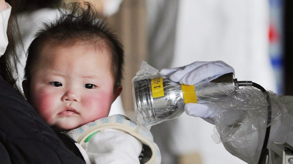 A baby is screened at an evacuation center for leaked radiation from the damaged Fukushima nuclear power plant in Japan on March 24, 2011.