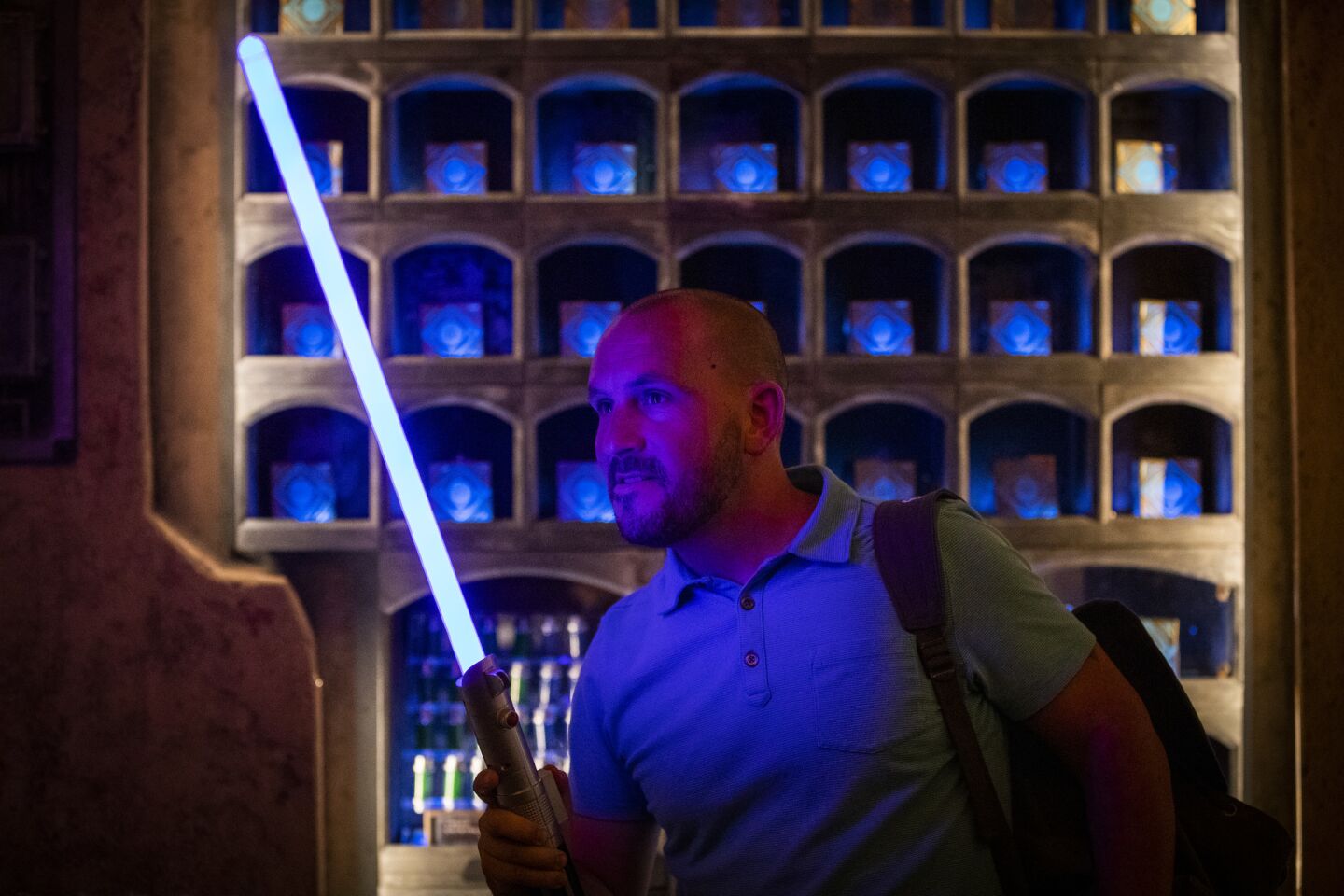 A member of the media holds a light saber for sale at the Dok-Ondar Den of Antiquities.
