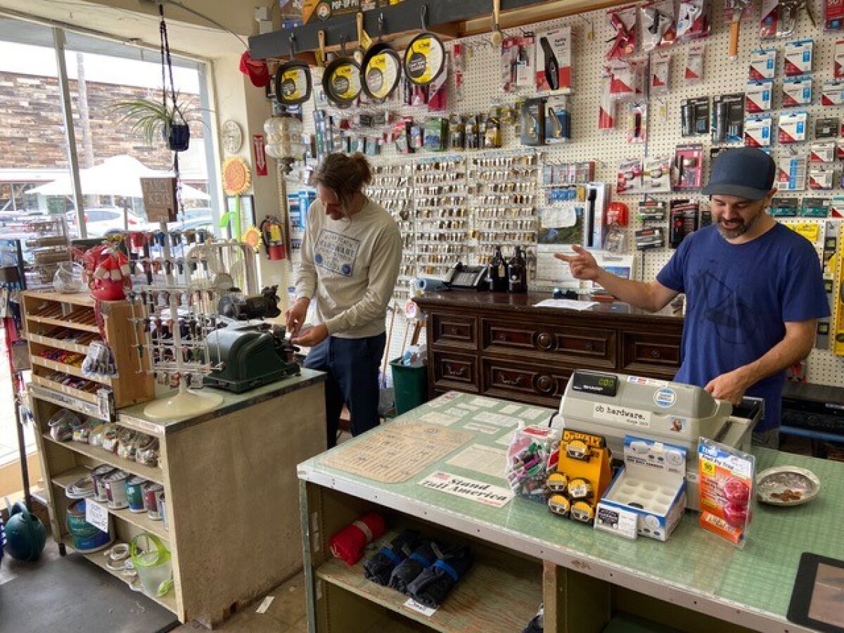 New co-owner Joe Kuchman (left) gets tips from departing owner Michael DeEmedio at the historical OB Hardware in Ocean Beach.