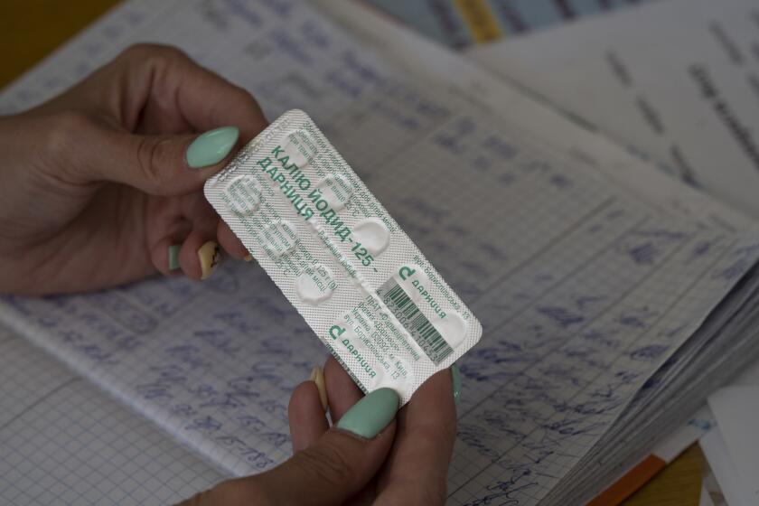 FILE - A woman shows a pack with iodine tablets before distributing them to residents at a local school in case of a radiation leak in Zaporizhzhia, Ukraine, Friday, Sept. 2, 2022. The war in Ukraine has heightened fears about nuclear exposure — and interest in iodine pills that can help protect the body from some radiation. (AP Photo/Leo Correa, File)