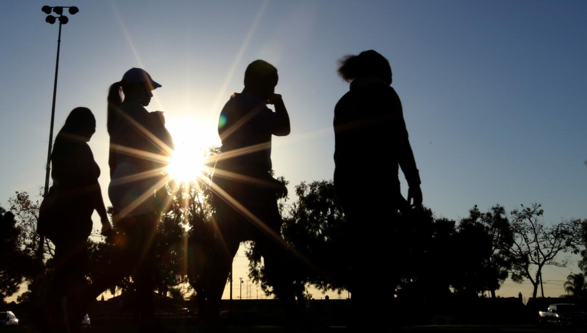 Walkers enjoy the setting sun at Liberty Park in Cerritos on Oct. 20. Temperatures soared above 90 degrees in some parts of Southern California on Wednesday.