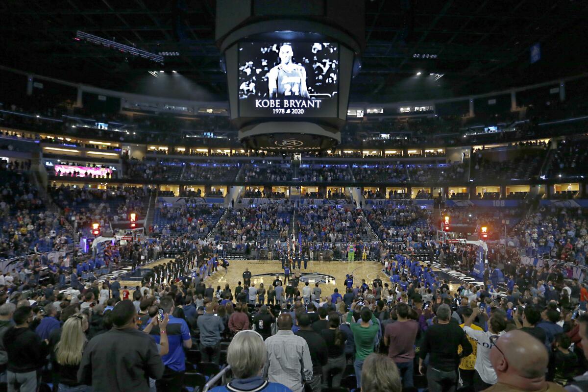 Fans honor the memory of Kobe Bryant with a moment of silence before an NBA basketball game between the Orlando Magic and the Los Angeles Clippers in Orlando, Fla.
