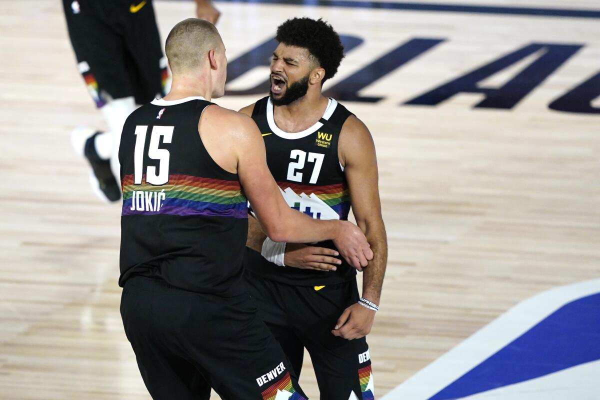 Nuggets guard Jamal Murray (27) and center Nikola Jokic (15) celebrate during their overtime defeat of the Jazz on Monday.