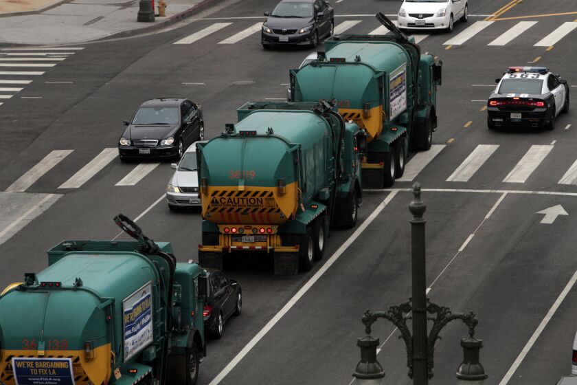 A convoy of garbage trucks participates in a July protest organized by L.A. unions.