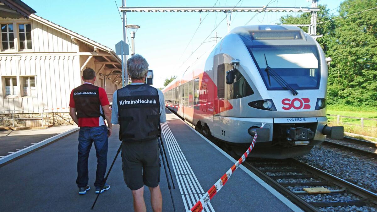 Police stand by a train at the station in Salez, eastern Switzerland, after a man set a fire and stabbed passengers.