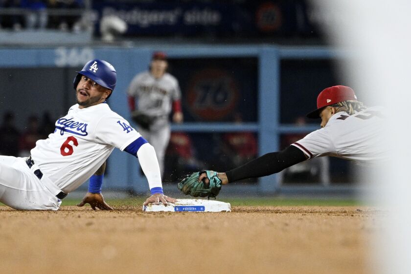 Los Angeles Dodgers' David Peralta, left, goes by the bag after being tagged out by Arizona Diamondbacks.
