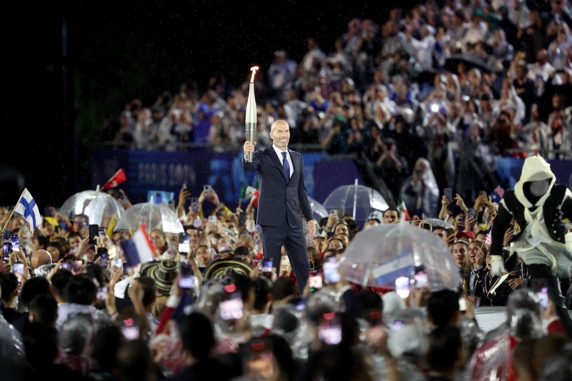 Zinedine Zidane, former French football player and manager, carries the Olympic Torch.