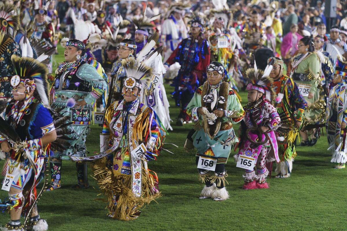 Dancers, singers and drummers in traditional regalia participating in a Native American powwow.