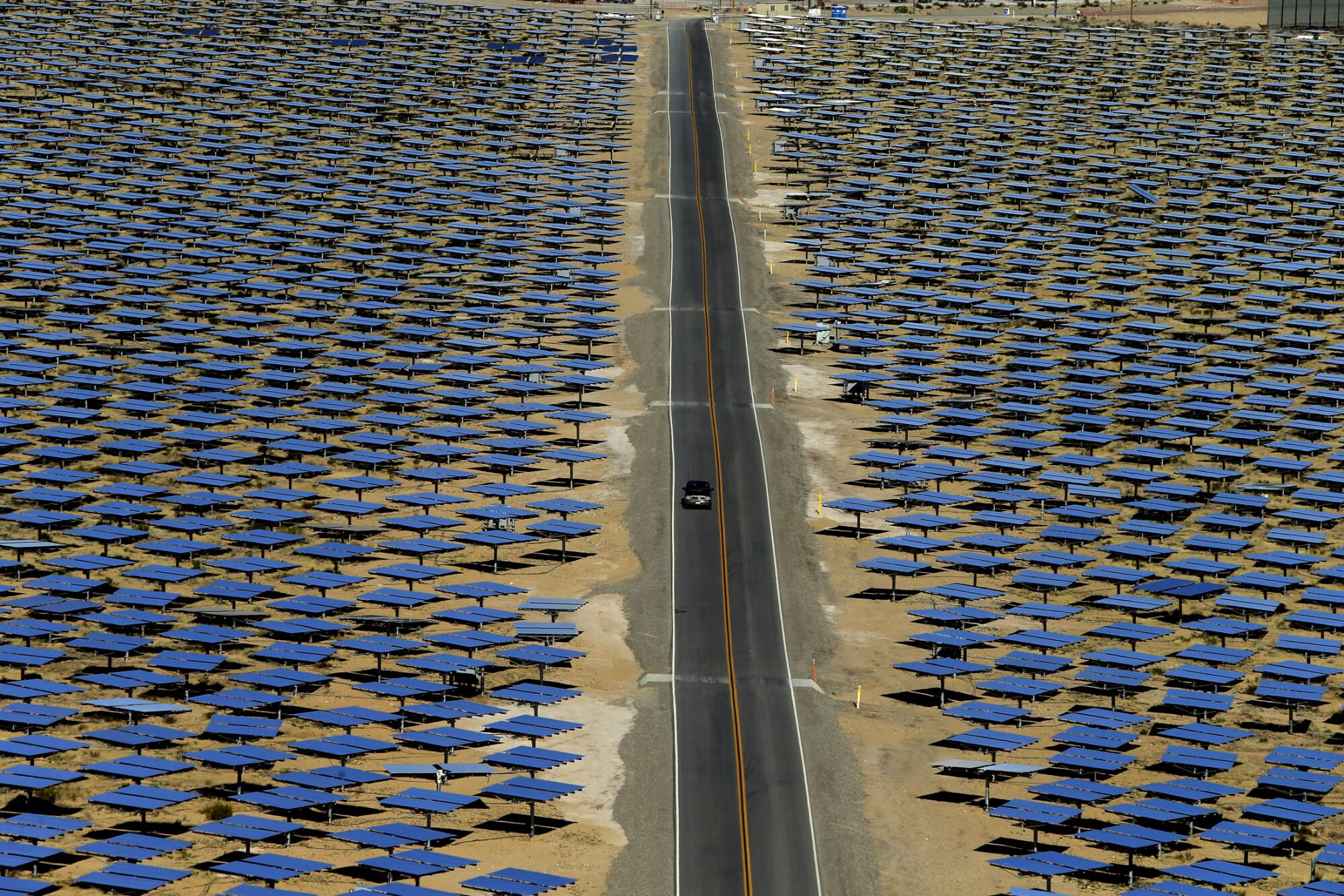 A desert road cuts through a vast array of solar energy mirrors.