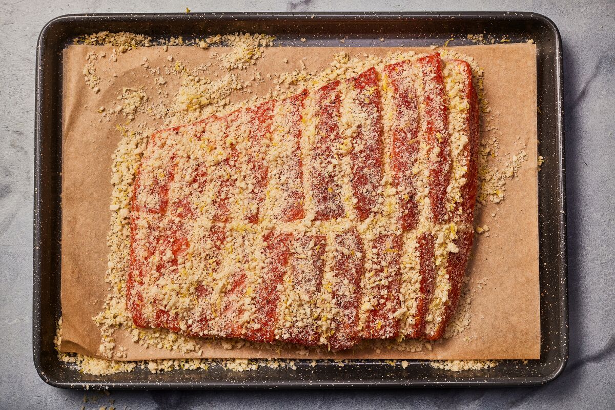Seasoned breadcrumbs are sprinkled over and tucked into the slits in hasselback salmon before it is baked.