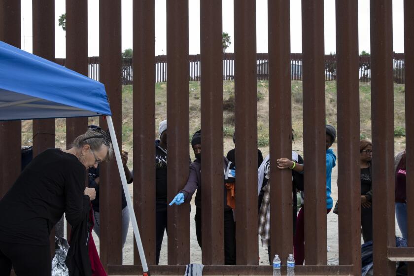 Jacumba, California - September 22: Volunteers hand clothing to about thirty women wait between the two fences at the U.S.-Mexico border to be processed by U.S. Border Patrol agents on Friday, Sept. 22, 2023 in Jacumba, California. (Ana Ramirez / The San Diego Union-Tribune)