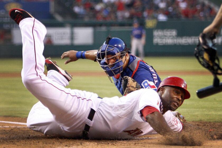 Torii Hunter scores a run for the Angels by reaching around the tag of catcher Yorvit Torrealba in a game against the Rangers.