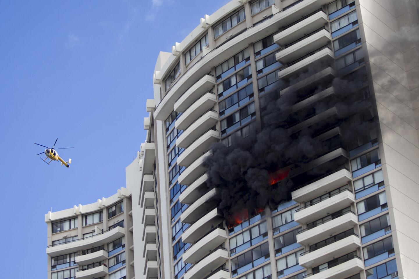 A Honolulu Fire Dept. helicopter flies near the burning Marco Polo apartment complex.