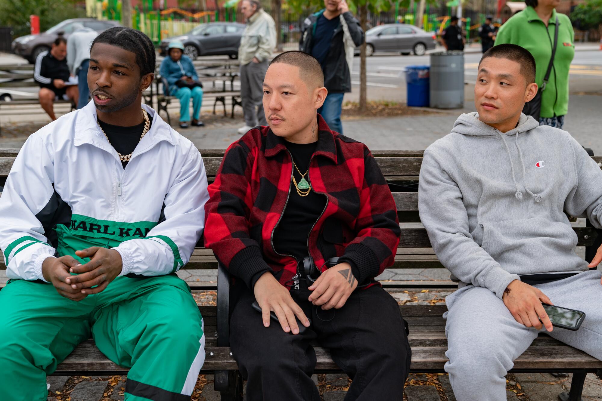 Pop Smoke Jackson, Eddie Huang and Taylor Takahashi sit on a city park bench.