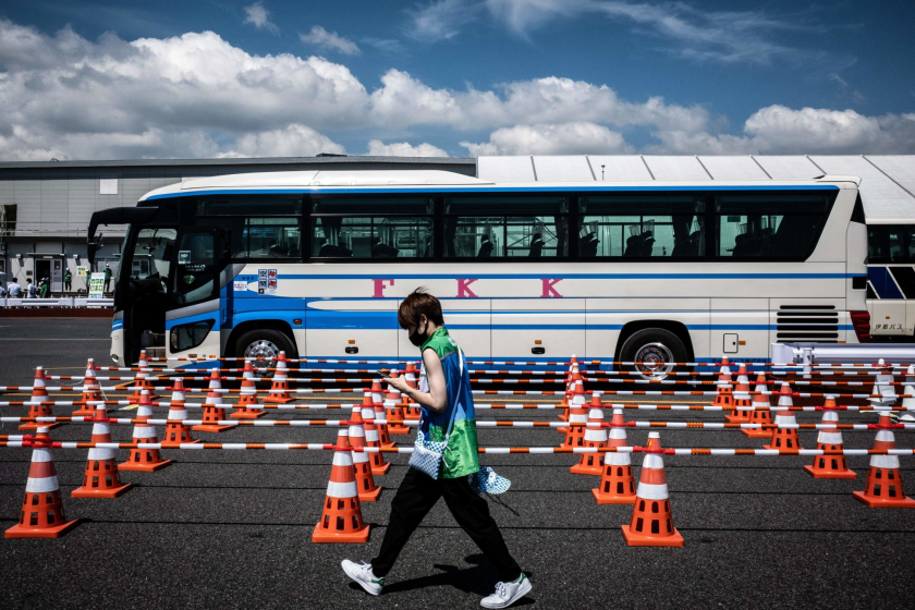 A volunteer passes by a bus at the Tokyo Olympic transportation mall.