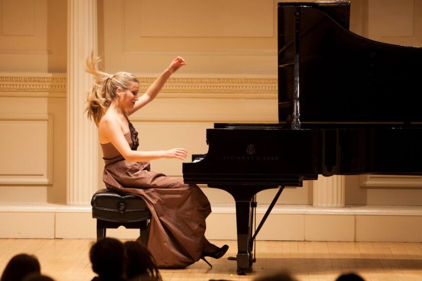A blonde woman in a fancy gown plays the piano, passionately
