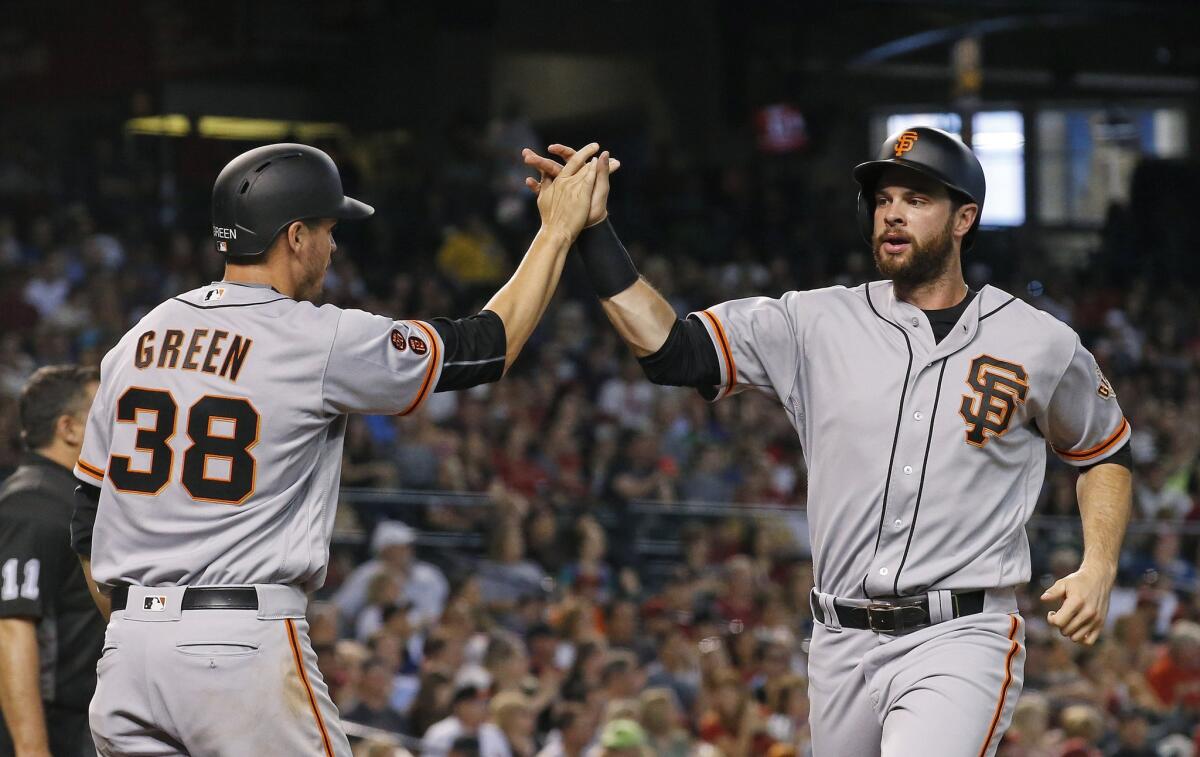 Giants first baseman Brandon Belt, right, and Grant Green (38) high-five after they scored runs against the Diamondbacks during the third inning of a game on July 3.
