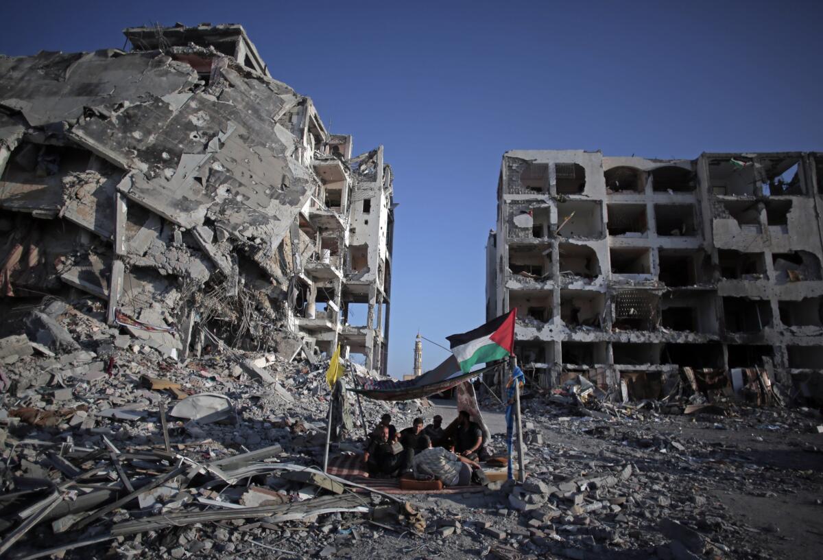 Palestinians sit in a makeshift shelter next to one of the destroyed Nada Towers apartment buildings in the Gaza town of Beit Lahiya on Aug. 11. Amnesty International on Wednesday accused Israel of committing war crimes during the recent war in Gaza.