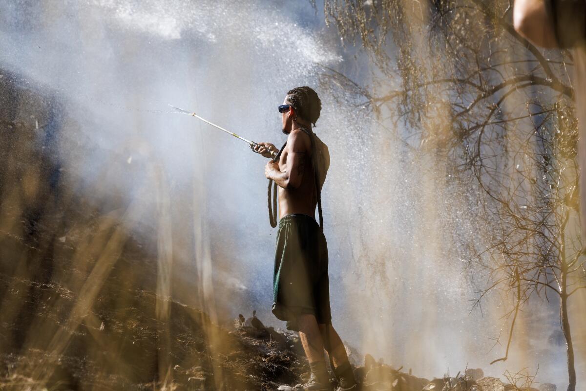 A resident uses a garden hose to help save a house on West Edgehill Road.