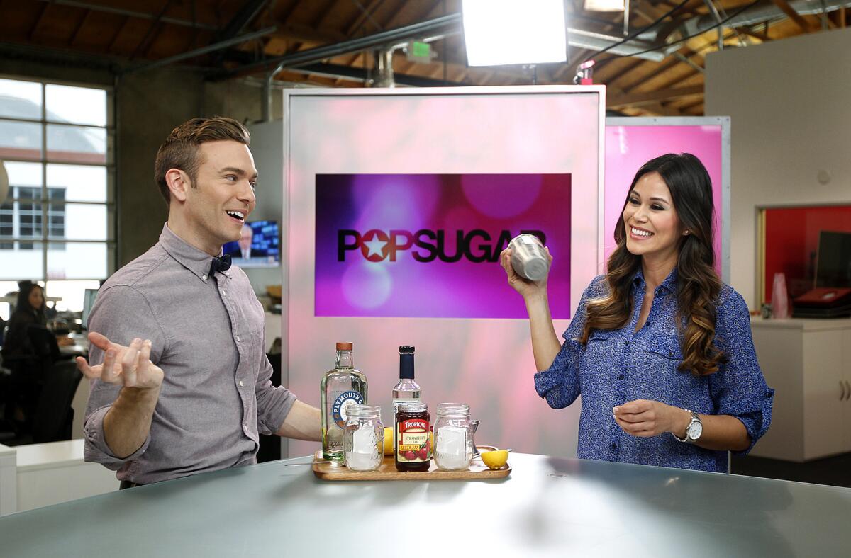 PopSugar entertainment reporter Matthew Rodrigues, left, and lifestyle reporter Brandi Milloy make a cocktail during PopSugar's "Happiest Hour" segment at their studios in Culver City.