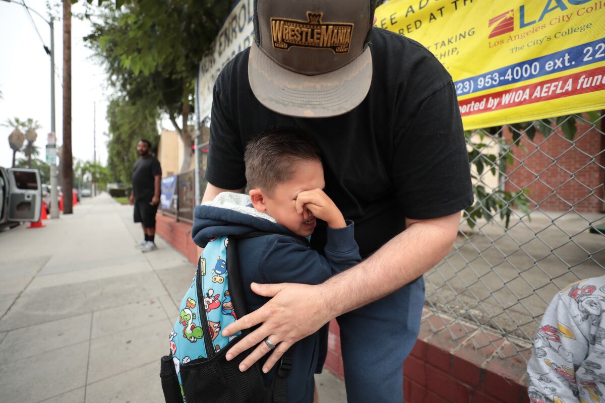 A 5-year-old boy tearfully hugs his father goodbye before school. 