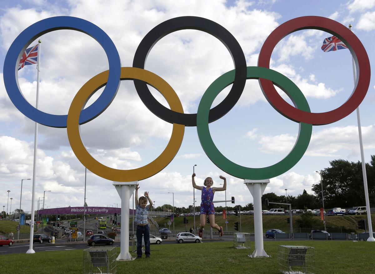 British children pose under a sculpture of the Olympics rings in Coventry on July 28, 2012.