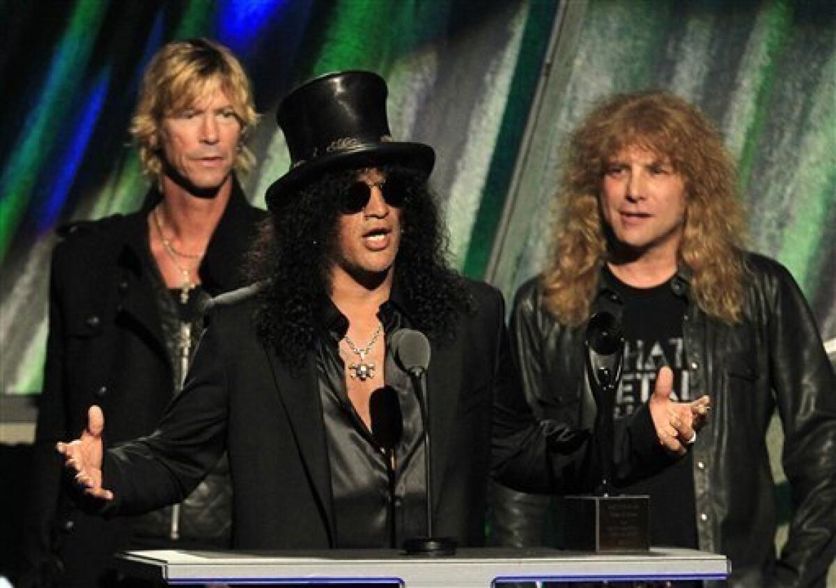 Guitarist Slash gestures with Duff McKagan, back left, and Steven Adler after Guns N' Roses was inducted into the Rock and Roll Hall of Fame Saturday, April 14, 2012, in Cleveland. (AP Photo/Tony Dejak)