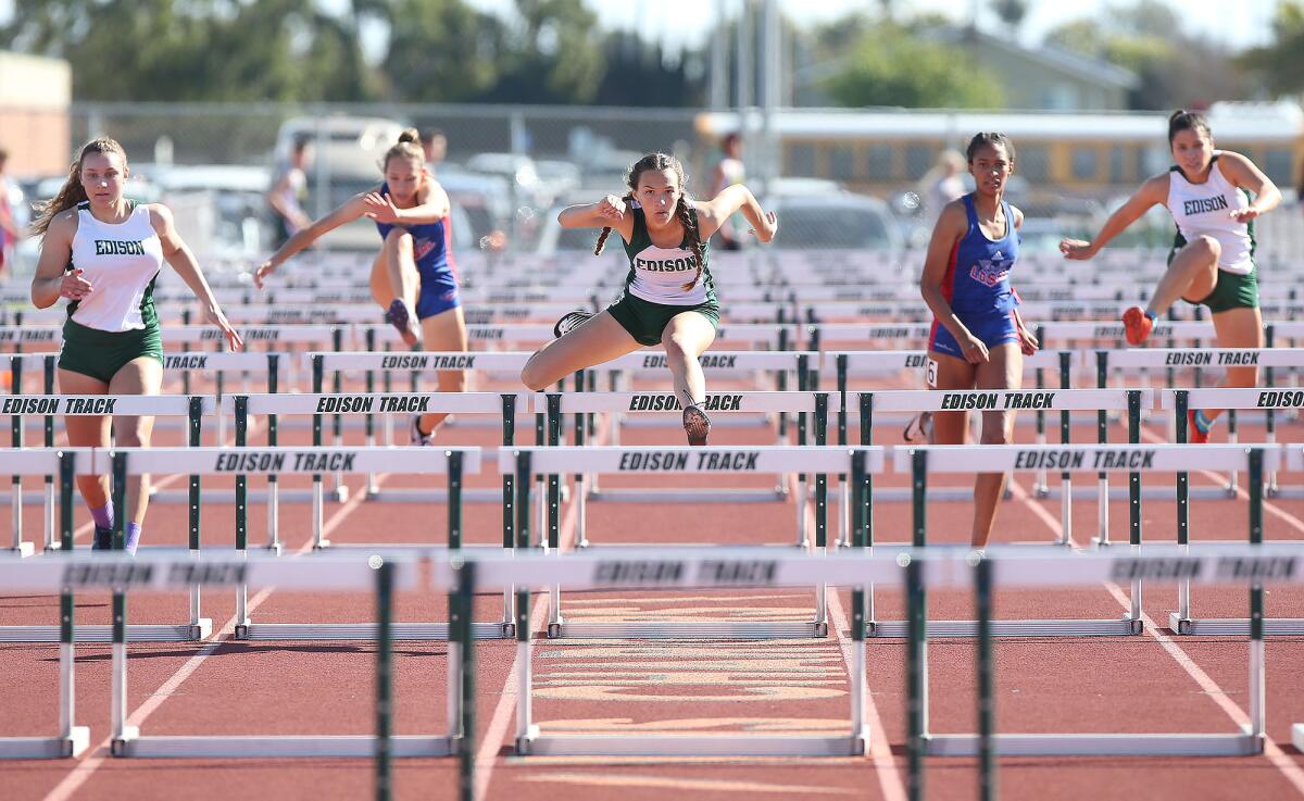 Edison's Megan Weiss, center, clears a hurdle en route to winning the 100-meter high hurdles during the Surf League dual meet against Los Alamitos on Wednesday.