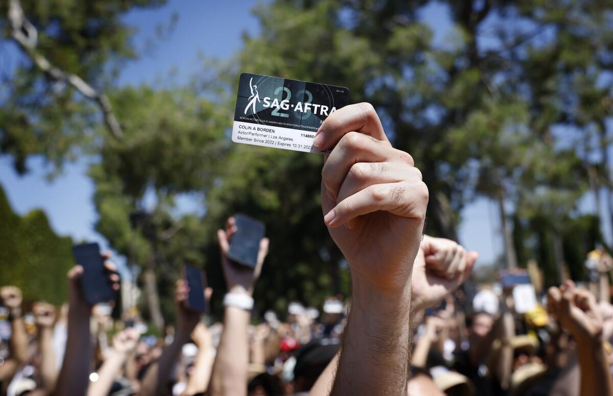 A hand holding up a SAG-AFTRA membership card at a strike rally.
