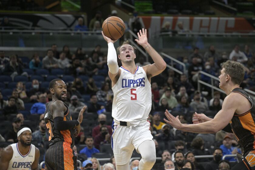 Los Angeles Clippers guard Luke Kennard (5) goes up for a shot between Orlando Magic guard Terrence Ross (31) and center Moritz Wagner (21) during the second half of an NBA basketball game, Wednesday, Jan. 26, 2022, in Orlando, Fla. (AP Photo/Phelan M. Ebenhack)