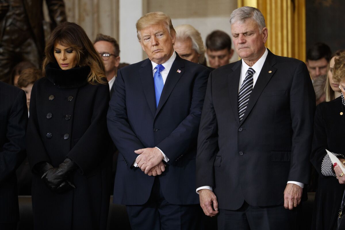First Lady Melania Trump, President Trump and the Rev. Franklin Graham pray during a ceremony honoring Graham's father, the late Rev. Billy Graham, in the Rotunda of the U.S. Capitol on Feb. 28, 2018.