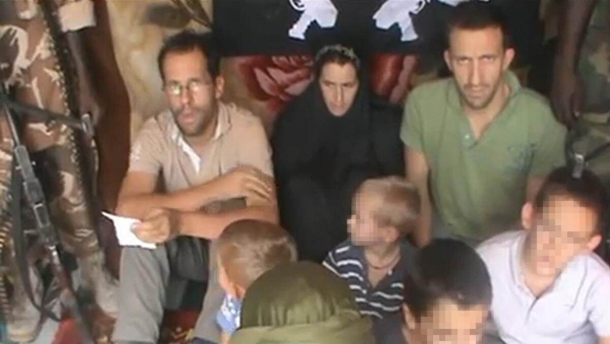 A picture taken from a YouTube video shows Tanguy Moulin-Fournier, left, sitting next to his wife, Albane (wearing a black veil), their four children and his brother Cyril, along with an armed man.