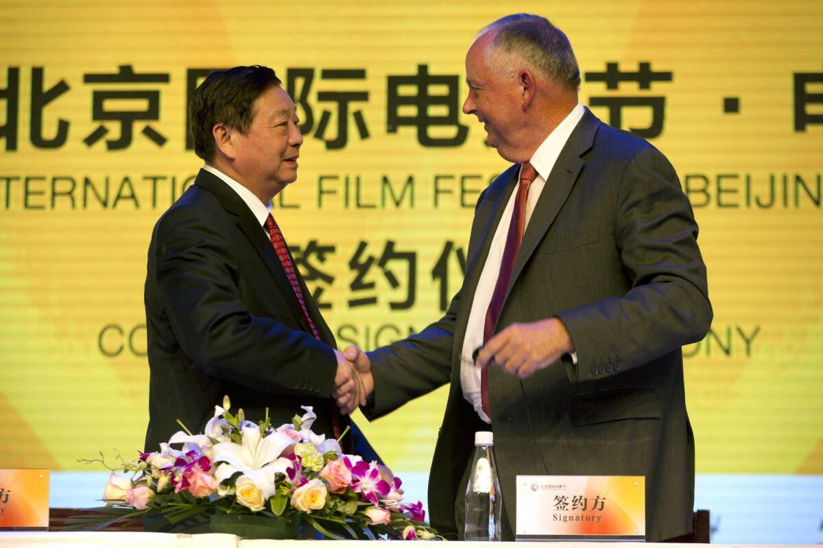 Li Shilin, left, head of China's CITIC Guoan, a unit of state-owned CITIC Group Corp., shakes hands with Dick Cook, former Walt Disney Studios chairman and current head of Dick Cook Studios.