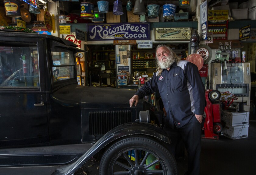 Joe Miracle, 70, the owner of Bay Auto Service in Costa Mesa, leans against his 1924 Chevrolet in his shop.