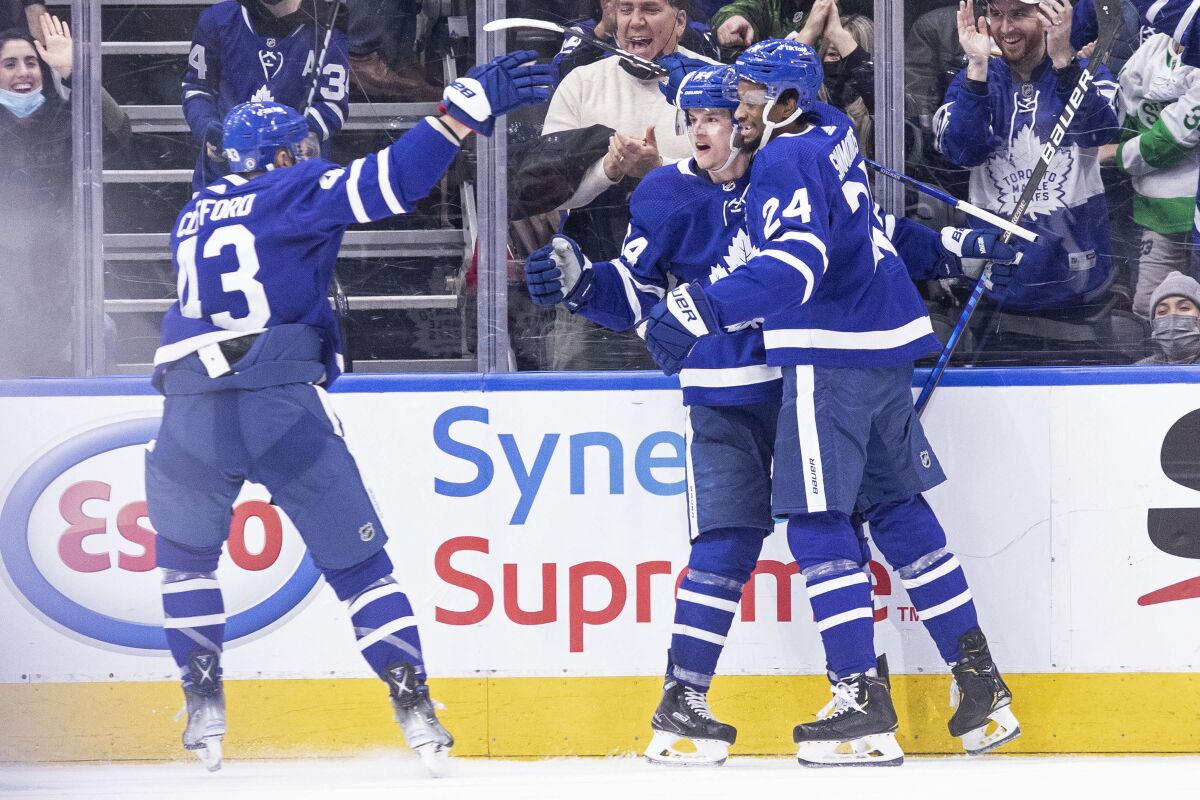 Toronto Maple Leafs' David Kampf, center, celebrates his goal against the Chicago Blackhawks with teammates Wayne Simmonds, right, and Kyle Clifford during third-period NHL hockey game action in Toronto, Saturday, Dec. 11, 2021. (Chris Young/The Canadian Press via AP)