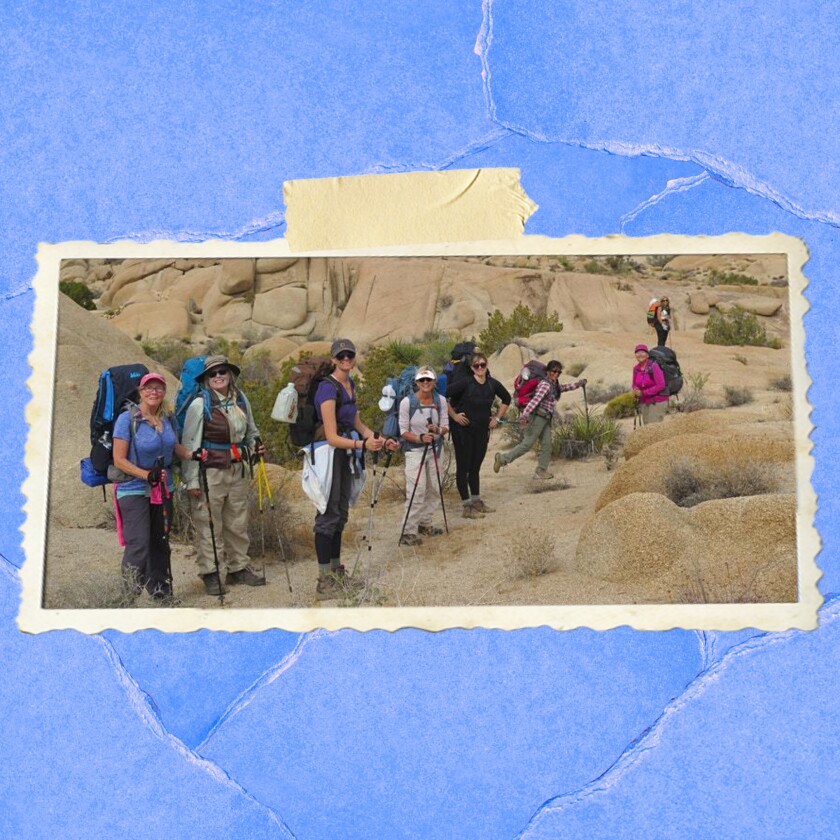 People with large backpacks stand amid a rocky landscape.