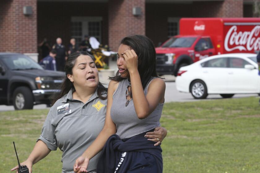 A student is comforted by a school official as students are led out of Forest High School after a shooting at the school on Friday, April 20, 2018 in Ocala, Fla. One student shot another in the ankle at the high school and a suspect is in custody, authorities said Friday. The injured student was taken to a local hospital for treatment. (Bruce Ackerman/Star-Banner via AP)