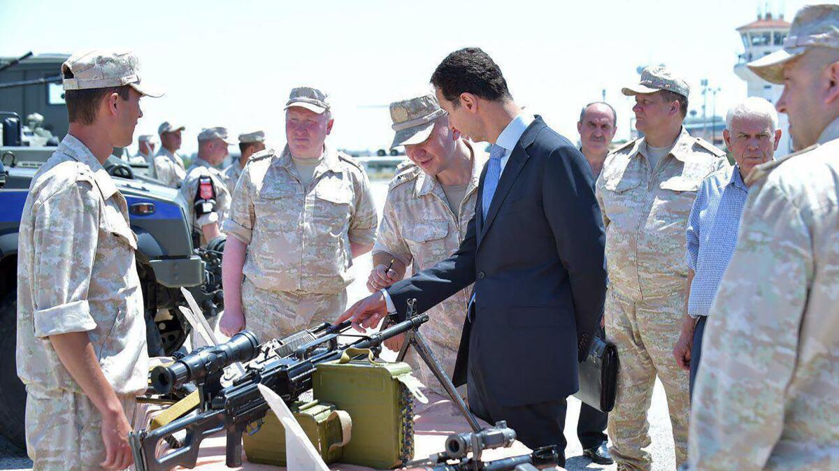 In a handout photo released on the Facebook page of the Syrian presidency on June 27, 2017, President Bashar Assad, center, inspects weapons at the Hmeimim military base in Latakia province, in northwest Syria.