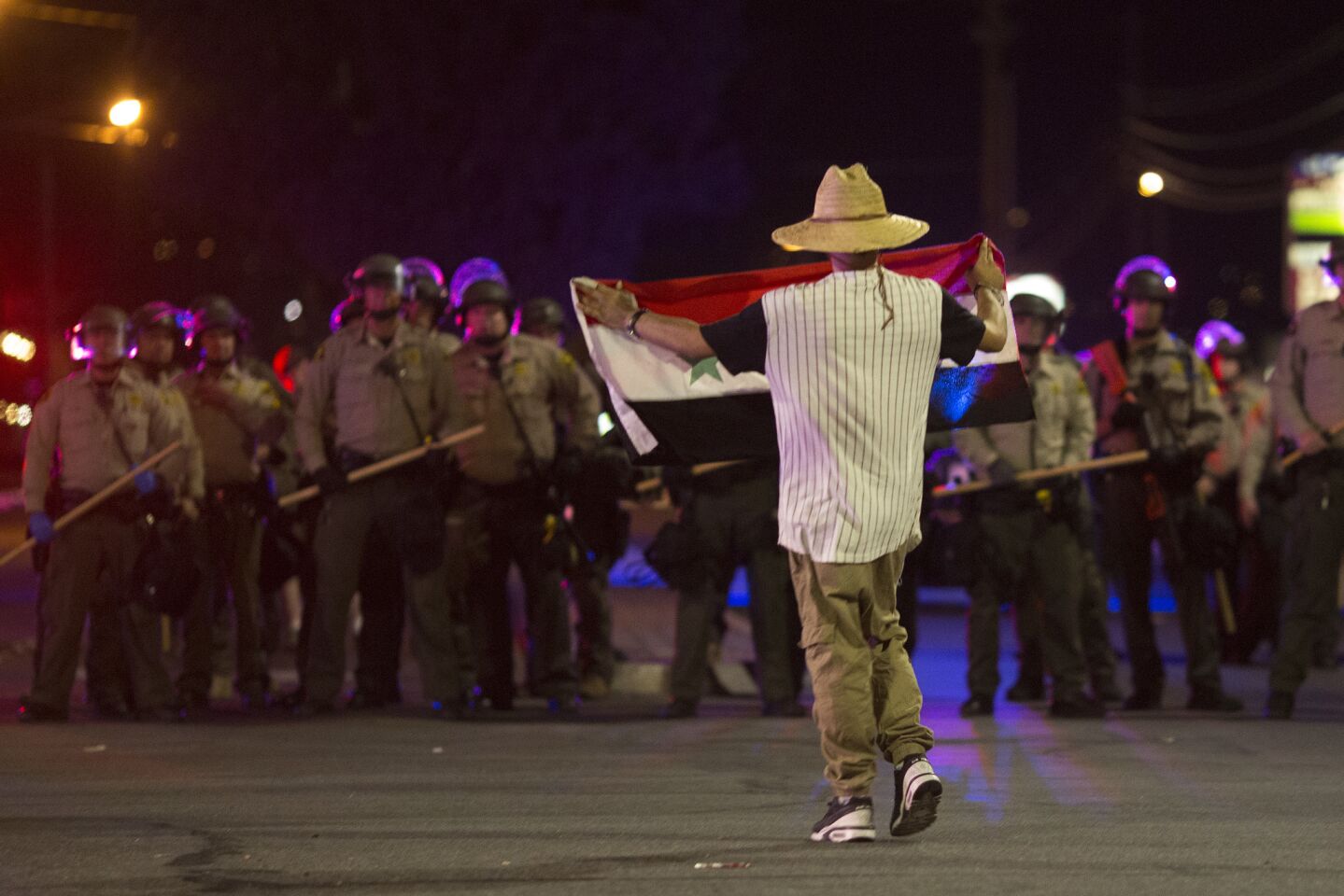 A protester walks toward sheriff's deputies in an intersection after an unlawful assembly was declared near the site where Alfred Olango had been shot by police earlier this week in El Cajon.