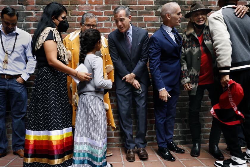 LOS ANGELES-CA-OCTOBER 11, 2021: Mayor Eric Garcetti, center, mingles with members of the Gabrieleno/Tongva Tribe, left, including nine-year-old Ellie Morales Recalde, in celebration of Indigenous People's Day, during a gathering of local tribal communities along with Councilmembers Mitch O'Farrell, to the right of Mayor Garcetti, and Kevin de Leon, not pictured, who joined Mayor Eric Garcetti to announce the beginning of a process to rename La Plaza Park informally known as Father Serra Park in downtown Los Angeles on Monday, October 11, 2021. An Indigenous Cultural Easement will also be created to give local indigenous communities priority access to the park for practice of traditional ceremonies. (Christina House / Los Angeles Times)