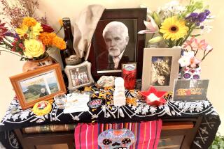 A table with bright textiles features flowers, photos of Mike Davis, Abuelita hot chocolate and a can of Coke