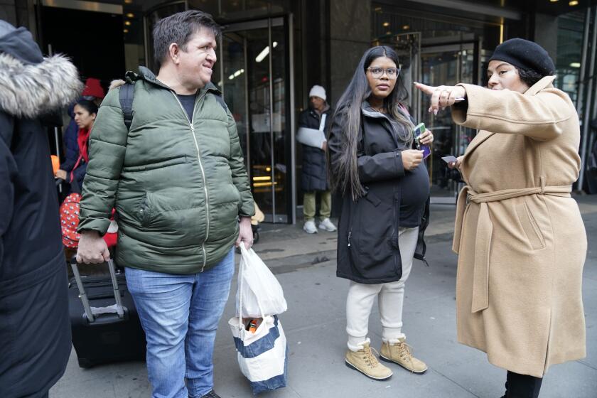 ARCHIVO - Los venezolanos David Quero, a la izquierda, y su pareja embarazada María Quero, en el centro, se marchan del Hotel Row con sus pertenencias, el martes 9 de enero de 2024, en Nueva York. (AP Foto/Mary Altaffer, Archivo)