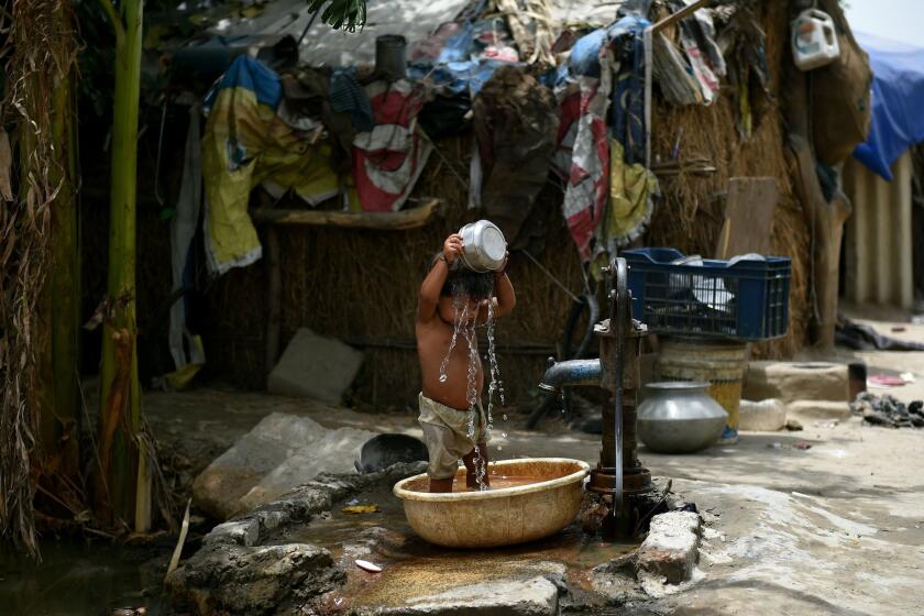 A child in New Delhi pours water on himself, trying to cool off.