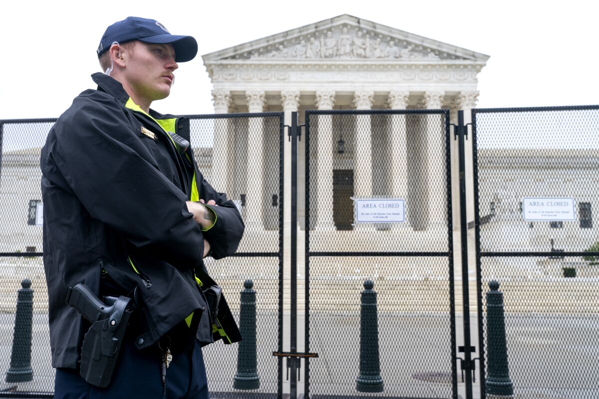 A Capitol Police officer stands next to a security fence outside the Supreme Court building