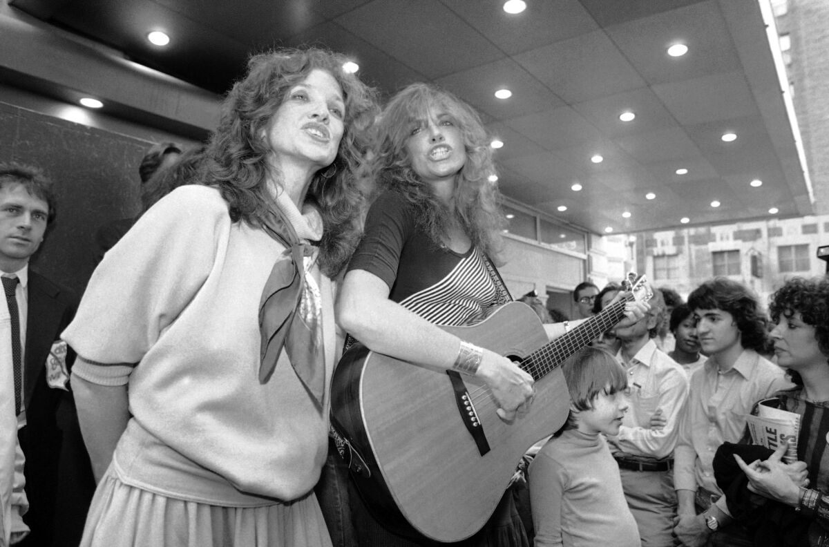 Two women performing with a guitar