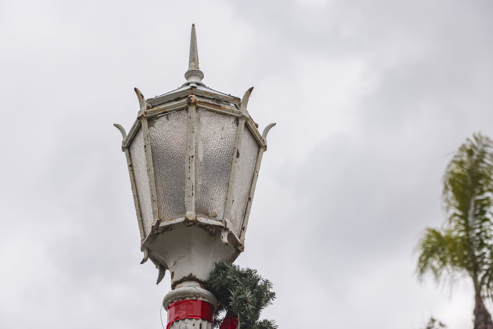 The lamp portion of an antique streetlight, with peeling paint and glass panels.